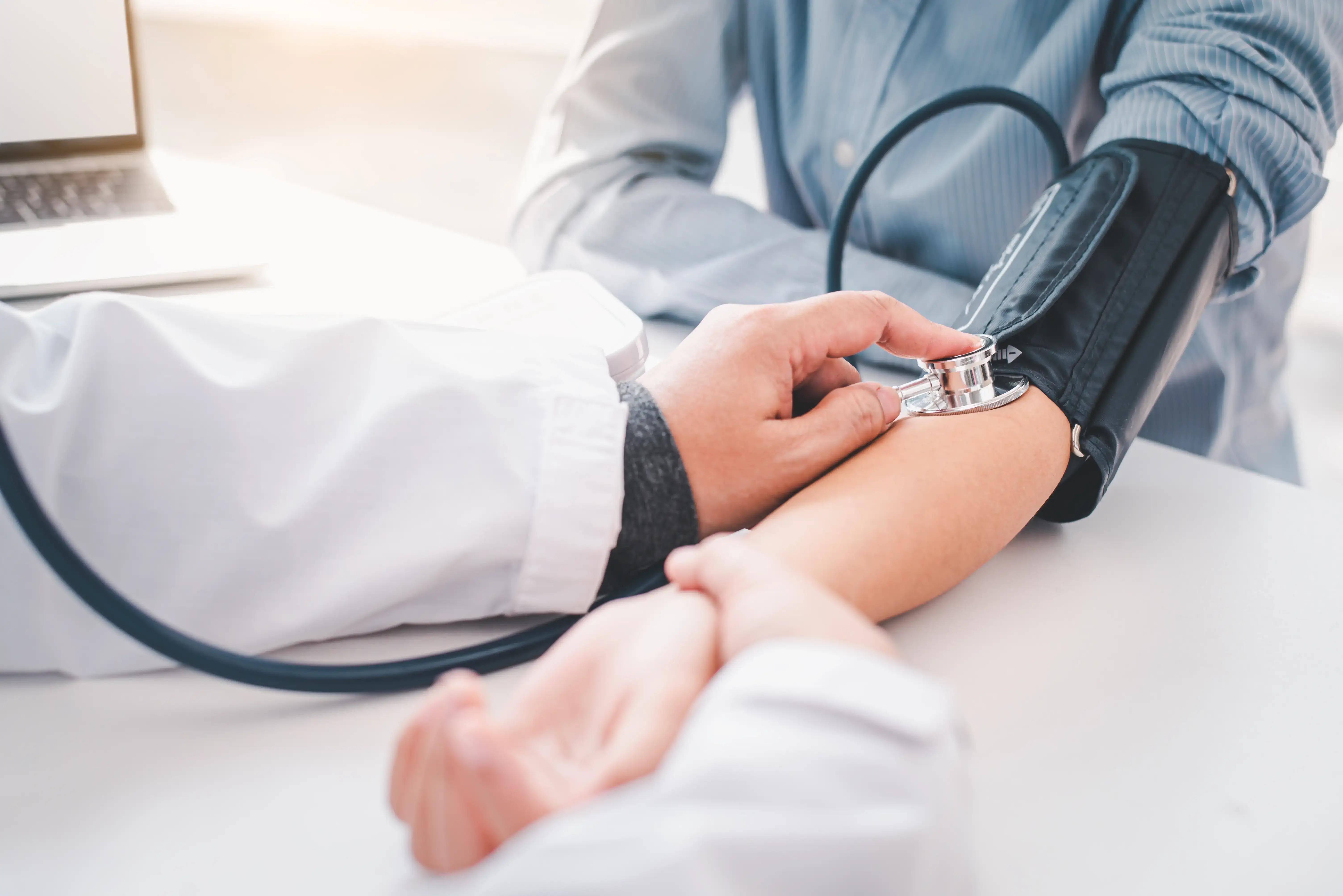 Doctor checks patient blood pressure in a clinical setting.