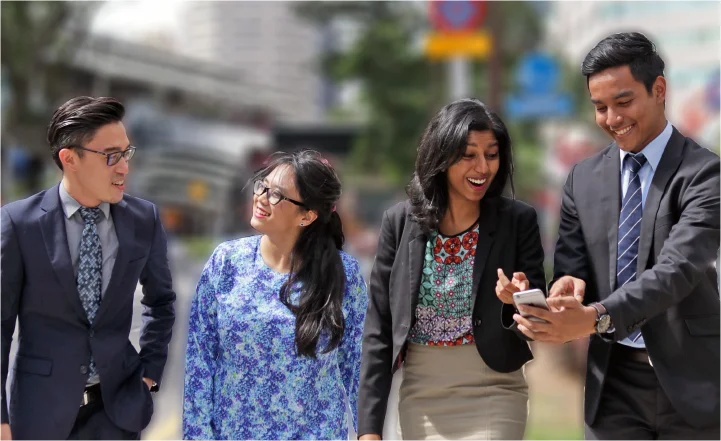 Four diverse young professionals walking and smiling together outdoors in the city