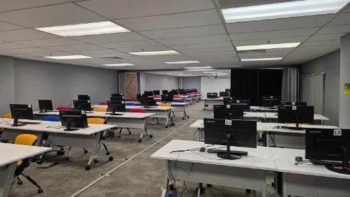 Computer lab with rows of desktop workstations and a large projector screen