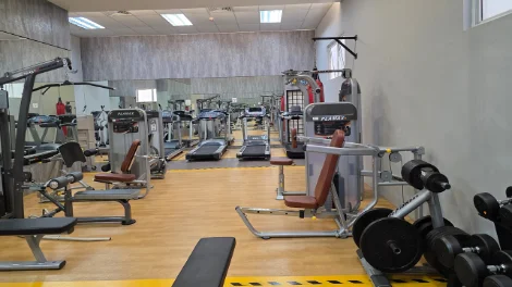 Well-equipped gymnasium with treadmills, weight machines and wooden flooring