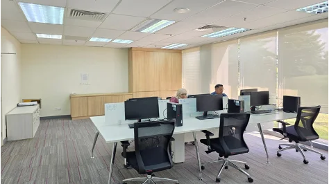 Open office workspace with desktop computers, ergonomic chairs and workstations